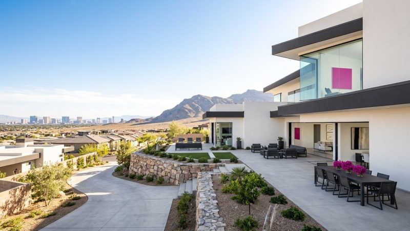 Modern luxury home with patio, desert landscaping, mountains, and the Las Vegas skyline in the distance.